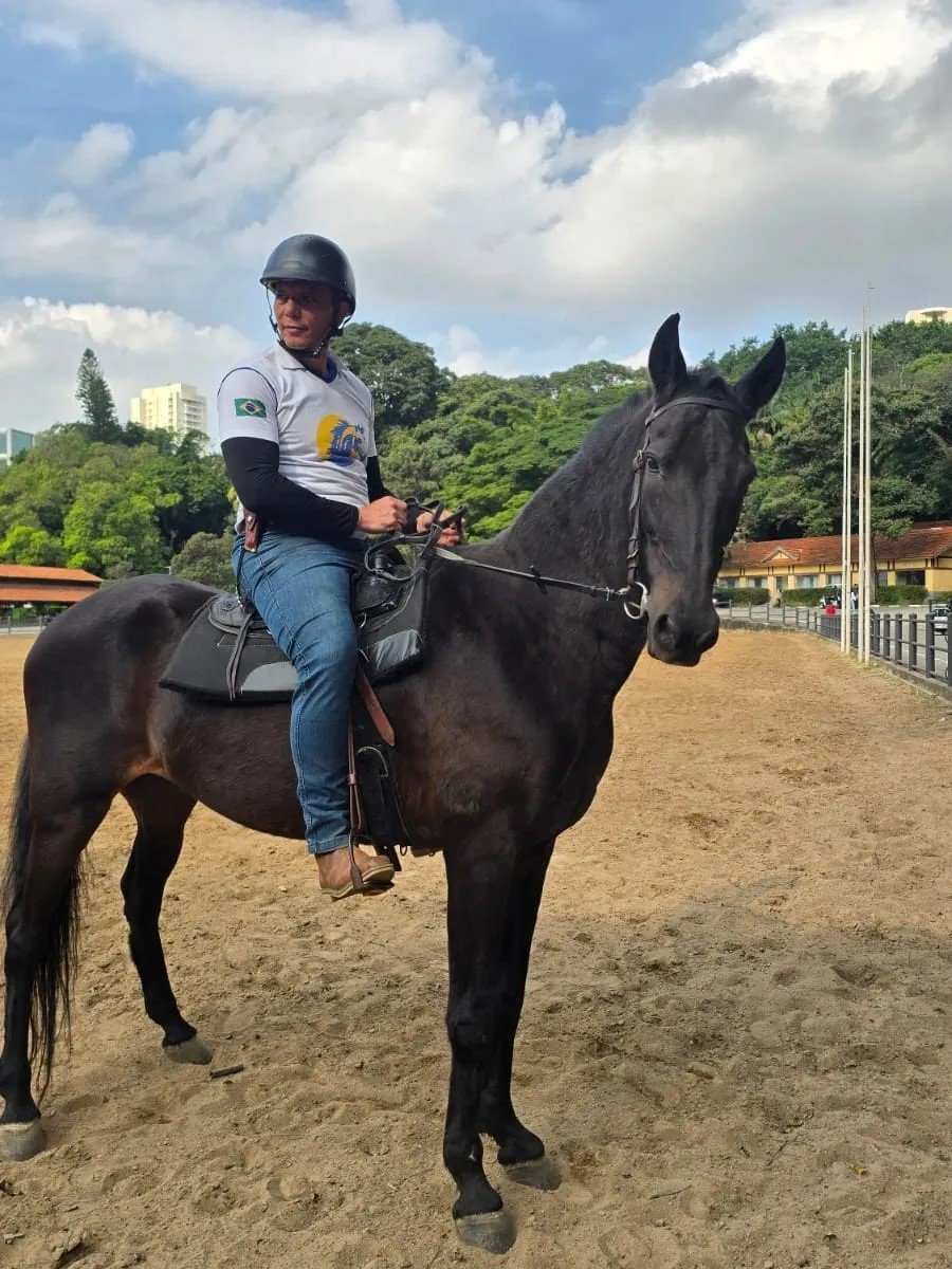 Homem usando capacete montado em um cavalo preto